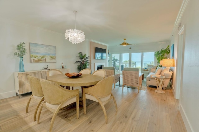 dining area with light hardwood / wood-style floors, ceiling fan with notable chandelier, and ornamental molding