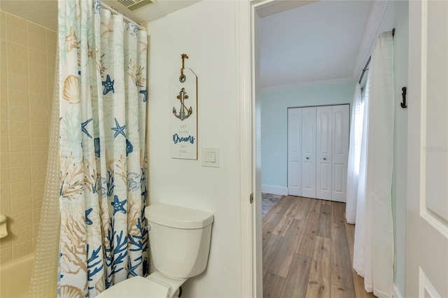 bathroom with wood-type flooring, toilet, and ornamental molding