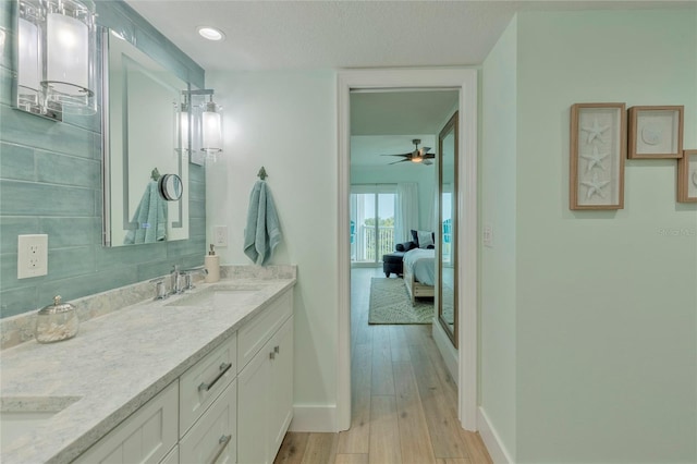 bathroom with wood-type flooring, vanity, tasteful backsplash, and ceiling fan