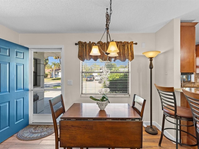 dining room with light hardwood / wood-style floors, an inviting chandelier, and a textured ceiling