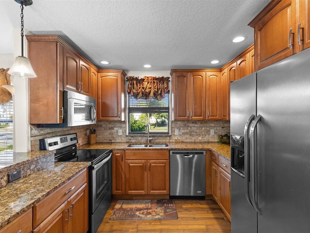 kitchen featuring appliances with stainless steel finishes, decorative light fixtures, decorative backsplash, and sink