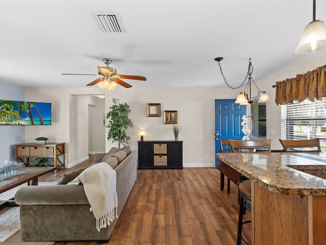 living room featuring dark hardwood / wood-style flooring and ceiling fan with notable chandelier