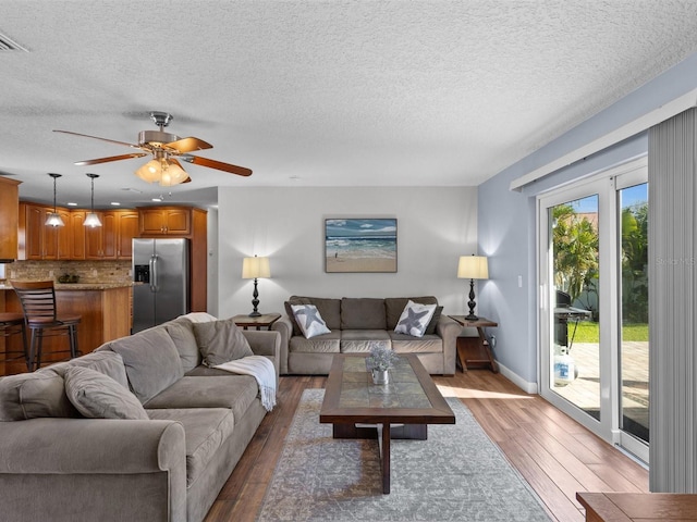 living room with a textured ceiling, hardwood / wood-style floors, and ceiling fan