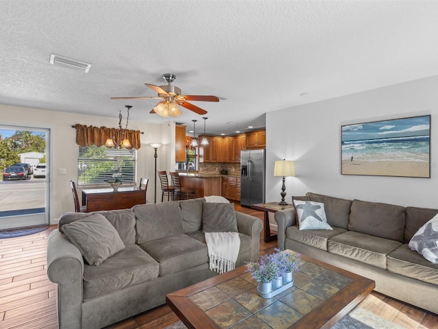 living room featuring a textured ceiling, ceiling fan, and hardwood / wood-style flooring