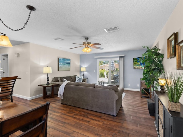 living room with ceiling fan, dark hardwood / wood-style flooring, and a textured ceiling