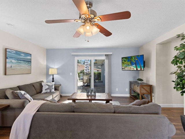 living room featuring dark wood-type flooring, a textured ceiling, and ceiling fan