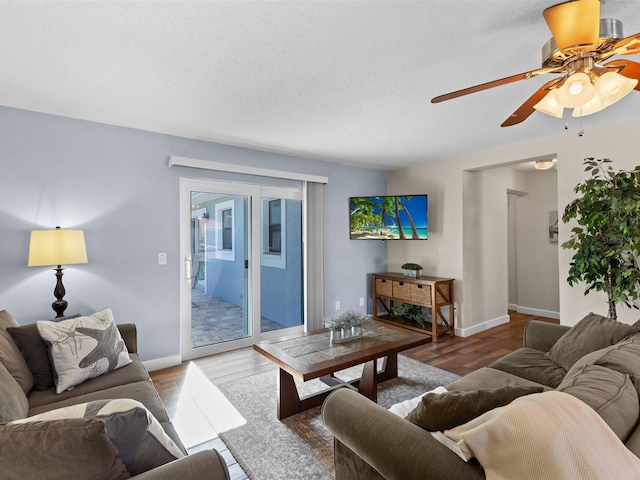 living room with a textured ceiling, ceiling fan, and hardwood / wood-style flooring