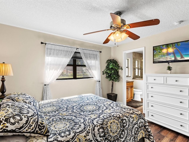 bedroom with a textured ceiling, ceiling fan, dark hardwood / wood-style flooring, and connected bathroom