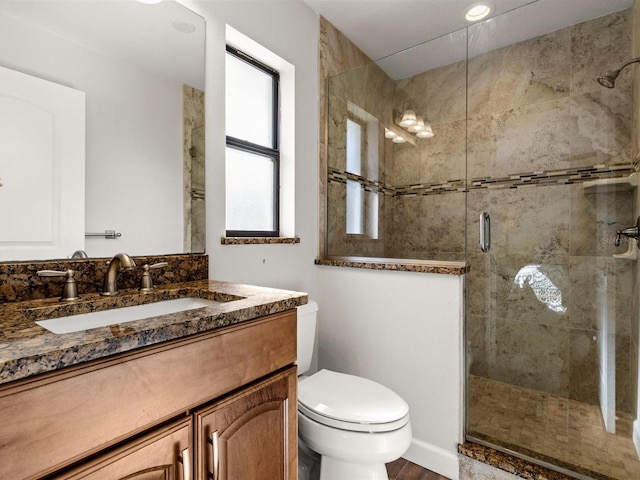 bathroom with vanity, hardwood / wood-style flooring, a shower with shower door, and toilet