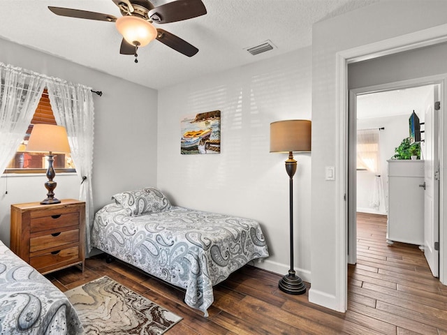 bedroom with ceiling fan, dark hardwood / wood-style flooring, and a textured ceiling