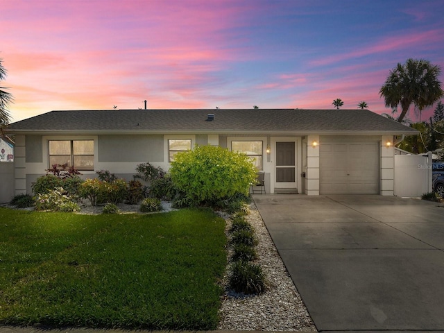 ranch-style home featuring a garage and a lawn