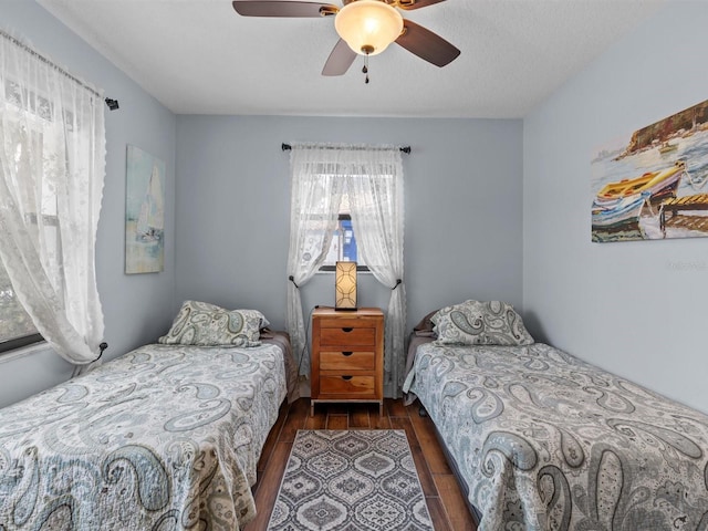 bedroom with ceiling fan, dark wood-type flooring, and a textured ceiling