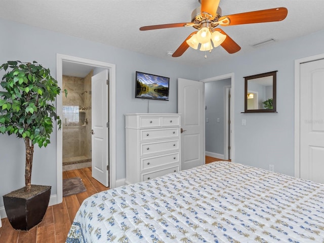 bedroom featuring ceiling fan, ensuite bath, and a textured ceiling