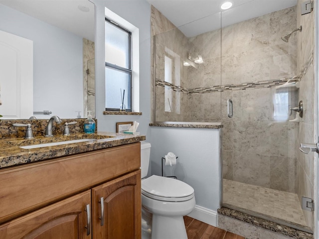 bathroom with toilet, vanity, and a shower with shower door