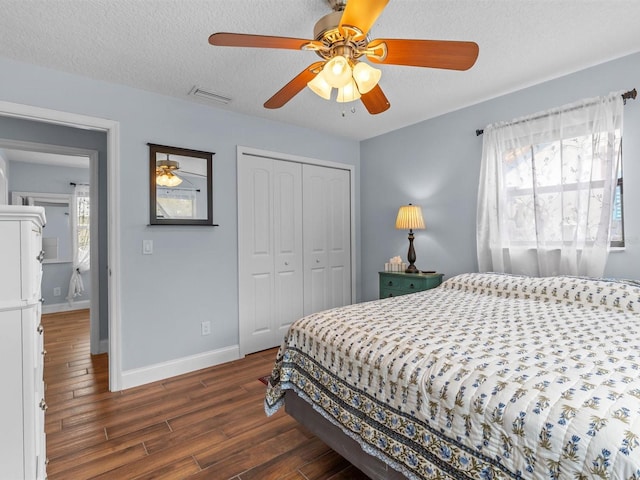 bedroom with dark wood-type flooring, a textured ceiling, ceiling fan, and a closet