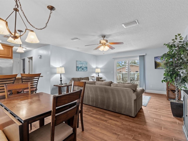 living room featuring a textured ceiling, ceiling fan with notable chandelier, and wood-type flooring