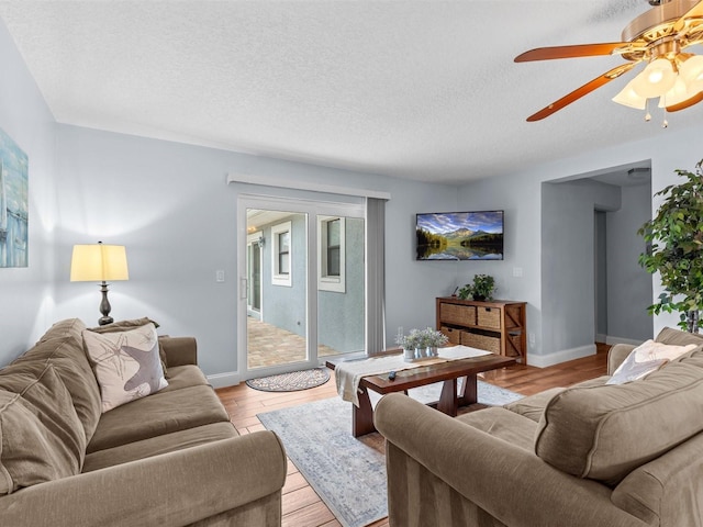 living room featuring a textured ceiling, ceiling fan, and light wood-type flooring