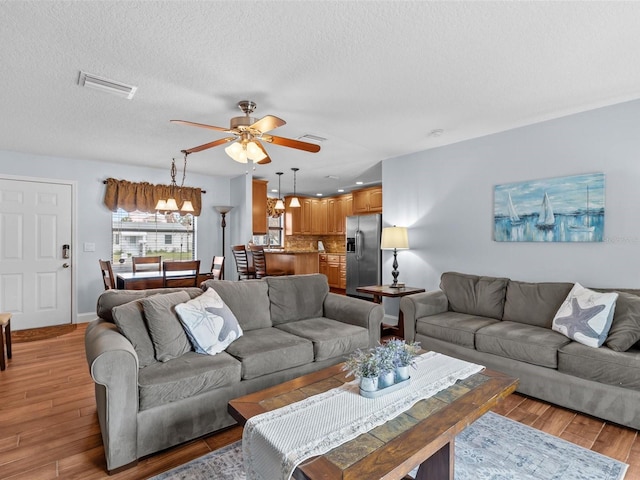 living room featuring a textured ceiling, ceiling fan, and light hardwood / wood-style floors