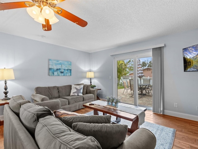 living room with light wood-type flooring, ceiling fan, and a textured ceiling