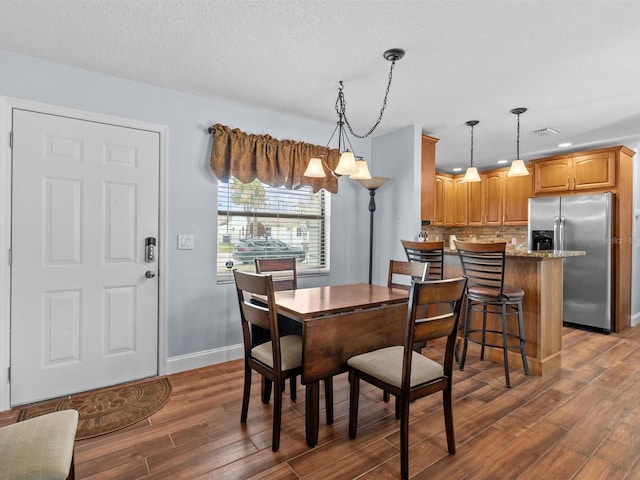 dining room with a textured ceiling, a chandelier, and dark hardwood / wood-style floors