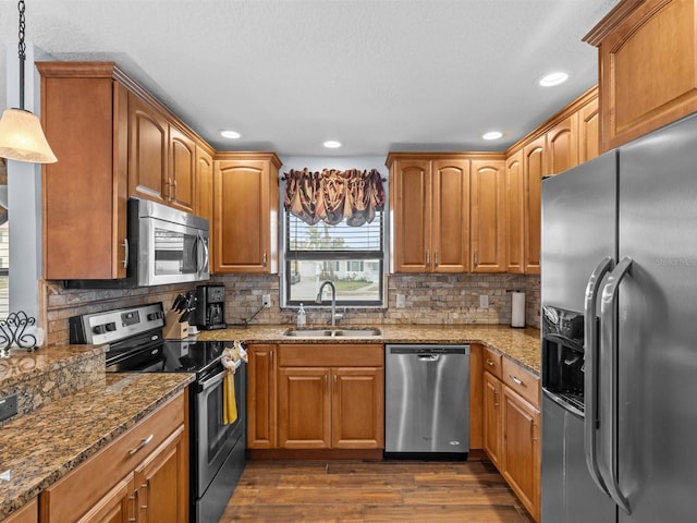 kitchen featuring dark wood-type flooring, pendant lighting, tasteful backsplash, appliances with stainless steel finishes, and sink