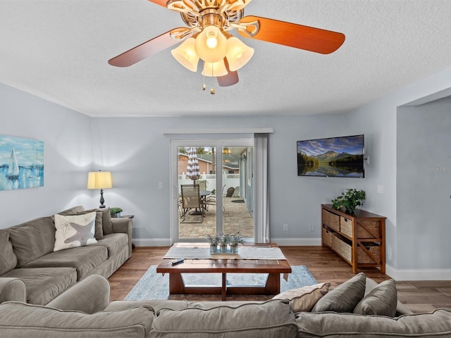 living room with a textured ceiling, ceiling fan, and light hardwood / wood-style flooring