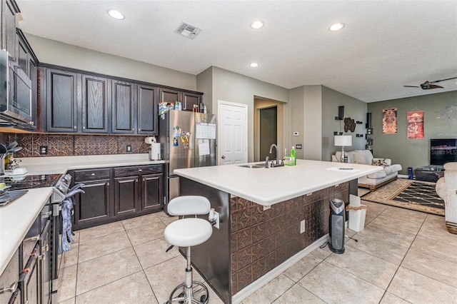 kitchen featuring sink, ceiling fan, an island with sink, a kitchen bar, and stainless steel appliances