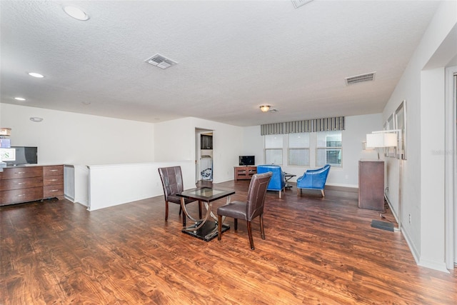 dining room featuring a textured ceiling and dark hardwood / wood-style flooring