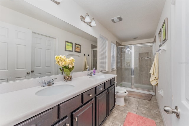 bathroom featuring a textured ceiling, vanity, toilet, and a shower with shower door