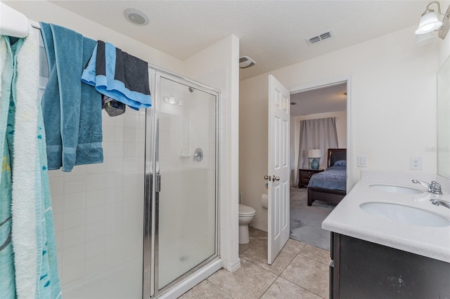 bathroom with tile patterned flooring, vanity, an enclosed shower, and toilet