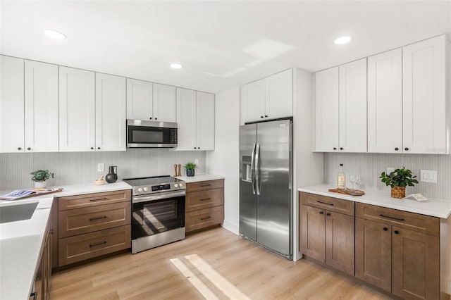 kitchen featuring white cabinets, light hardwood / wood-style floors, and appliances with stainless steel finishes