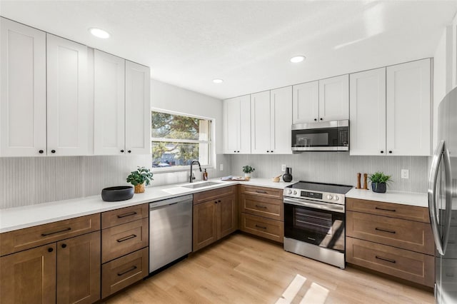 kitchen featuring white cabinets, appliances with stainless steel finishes, light hardwood / wood-style floors, and sink