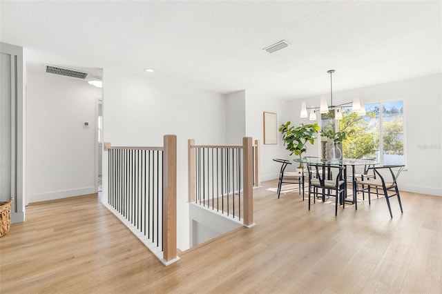 dining room with light wood-type flooring and a notable chandelier