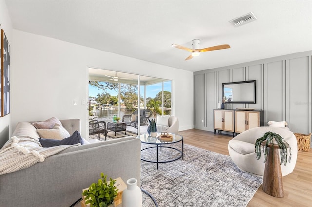 living room featuring ceiling fan, a water view, and light hardwood / wood-style floors