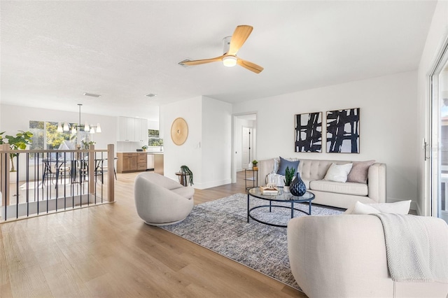 living room featuring light hardwood / wood-style flooring and ceiling fan with notable chandelier