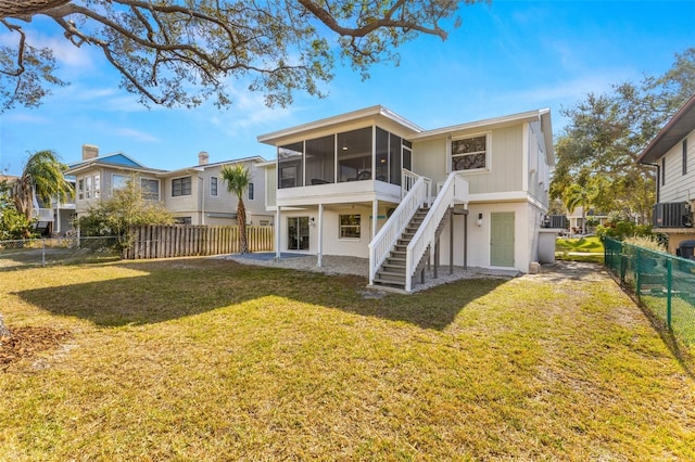 rear view of house with central air condition unit, a patio area, a sunroom, and a yard