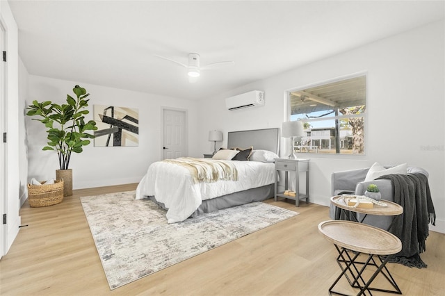 bedroom with light wood-type flooring, an AC wall unit, and ceiling fan