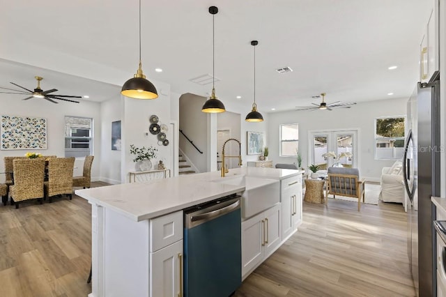 kitchen featuring sink, white cabinetry, hanging light fixtures, stainless steel appliances, and a kitchen island with sink