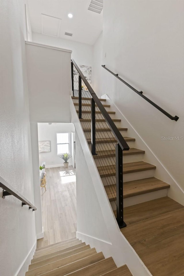 staircase with hardwood / wood-style floors and a towering ceiling