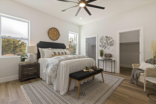 bedroom with ceiling fan, wood-type flooring, and multiple windows