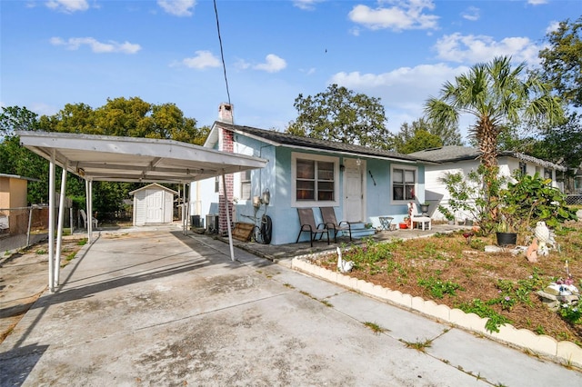 view of front of house with a carport, a storage shed, and central air condition unit