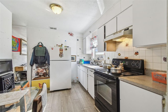 kitchen featuring white cabinetry, decorative backsplash, white refrigerator, black range with electric cooktop, and light wood-type flooring