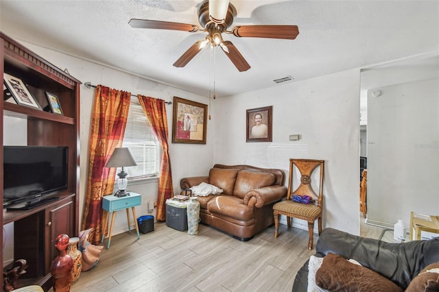 living room with a textured ceiling, light hardwood / wood-style flooring, and ceiling fan