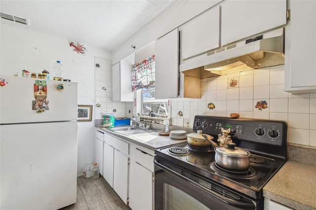 kitchen with decorative backsplash, black electric range, white cabinets, and white refrigerator