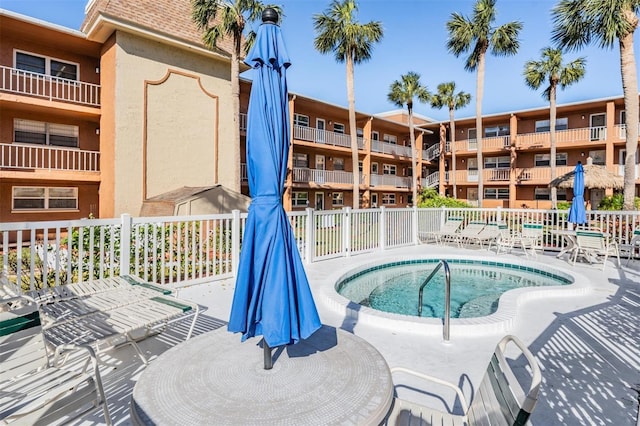 view of swimming pool featuring a hot tub and fence