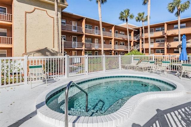 view of pool featuring a community hot tub and fence