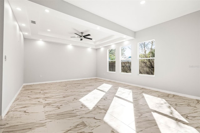 spare room with a tray ceiling and ceiling fan