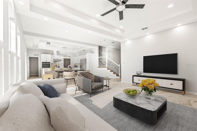 living room with a tray ceiling and ceiling fan