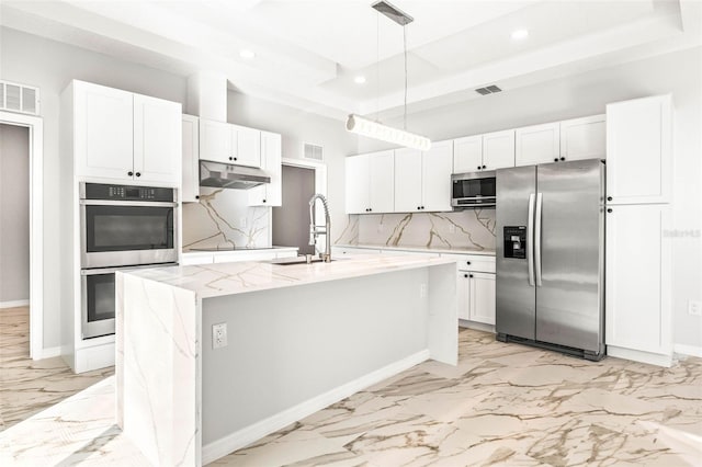 kitchen featuring stainless steel appliances, sink, white cabinets, hanging light fixtures, and an island with sink