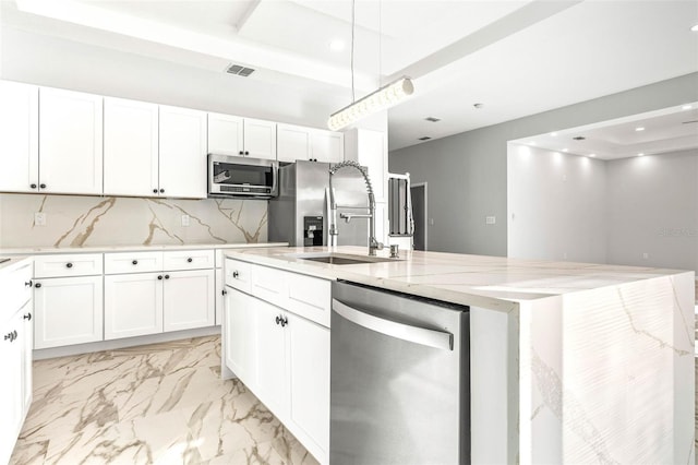 kitchen with light stone counters, stainless steel appliances, sink, a center island with sink, and white cabinets